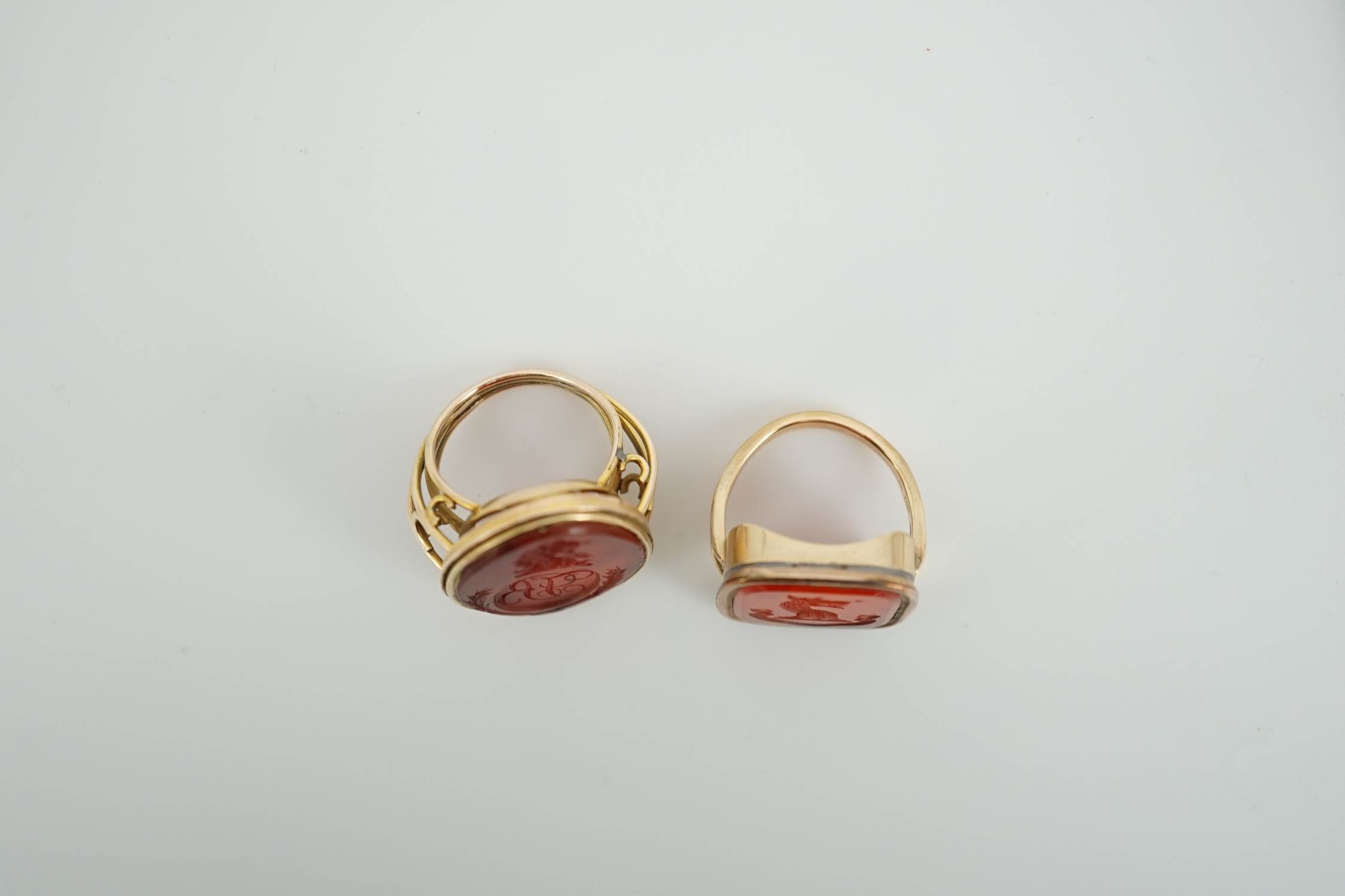 Two Victorian yellow metal and agate set intaglio rings, both matrix carved with a crest, one with monogram also, sizes K and L, gross weight 21.5 grams.